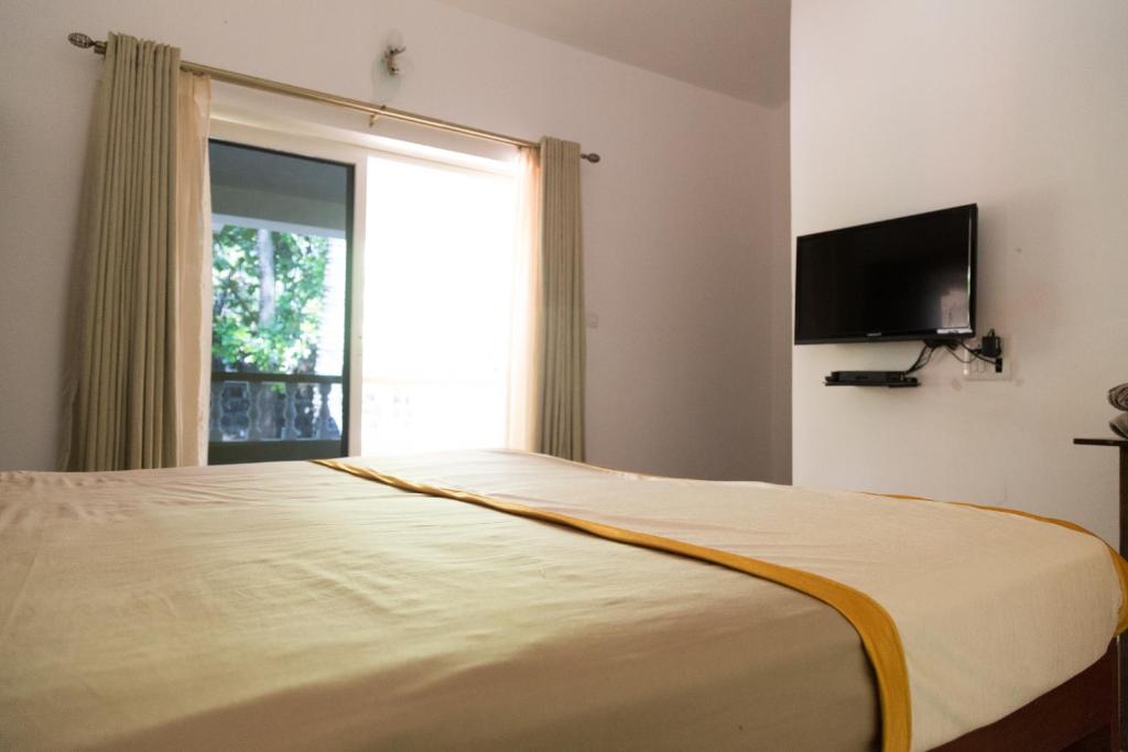 Un dormitorio con una cama grande con una ventana grande. en Hill Top Goa Lodge, en Vagator