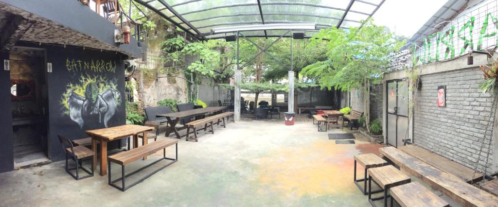 a patio with benches and tables in a building at Bat & Arrow in Padang