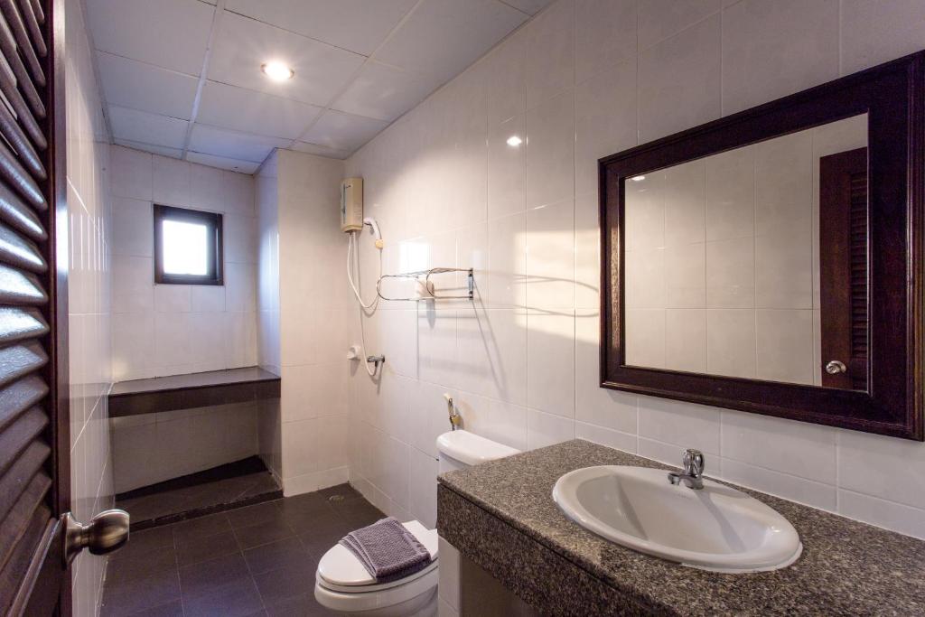 un bagno con lavandino, water e specchio di Surin Sunset Hotel - SHA a Surin Beach