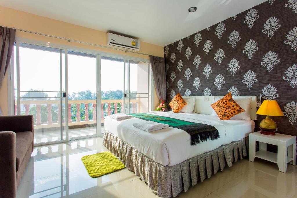 una camera con un grande letto e un balcone di Surin Sunset Hotel - SHA a Surin Beach