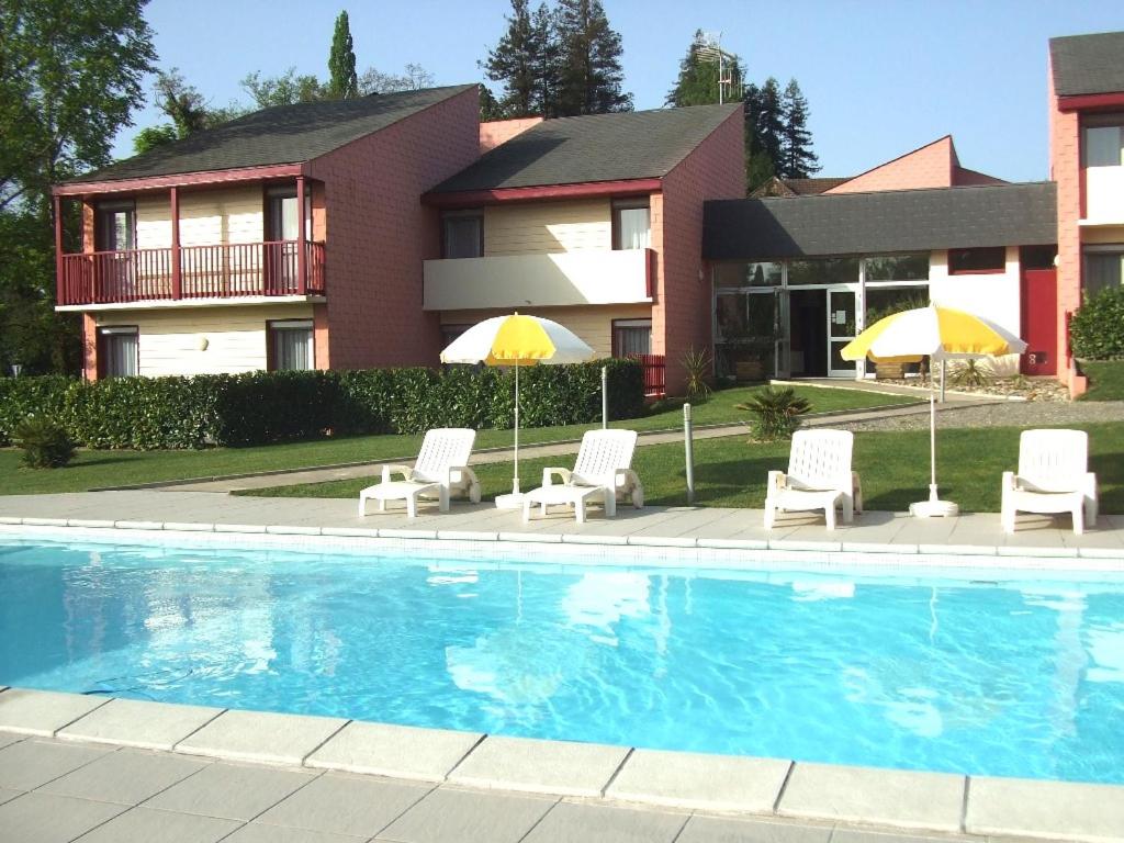 a pool with chairs and umbrellas in front of a house at Les Pavillons du Rooy in Salies-de-Béarn