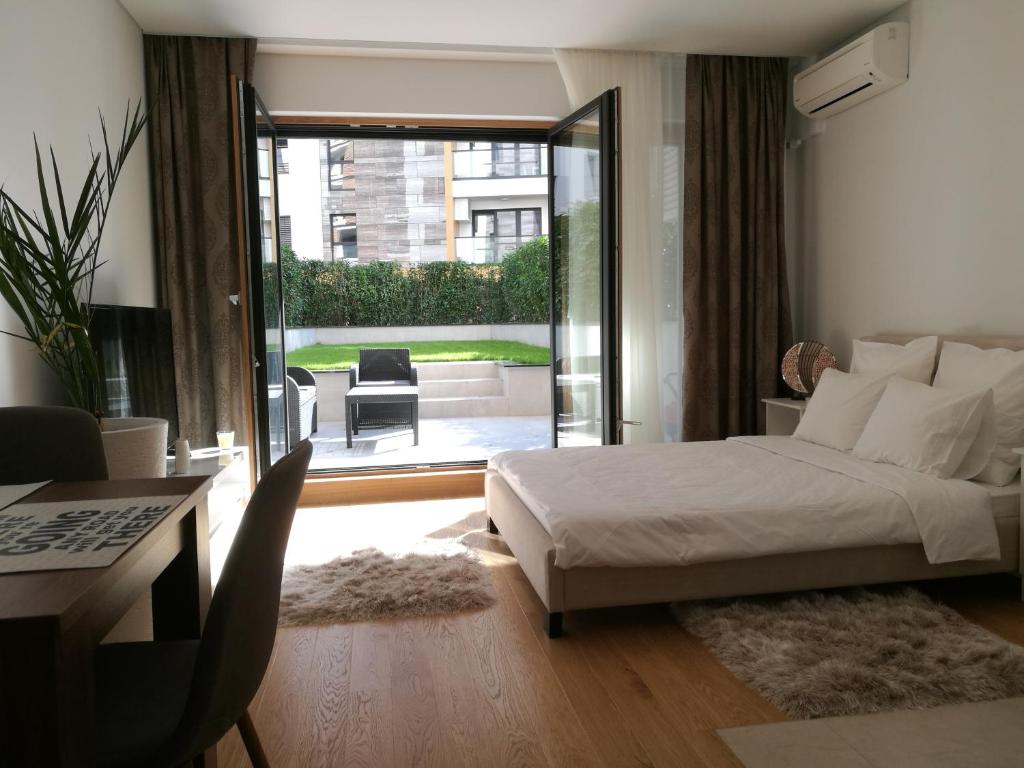 een slaapkamer met een bed en uitzicht op een patio bij Garden Apartment Sun City in Belgrado