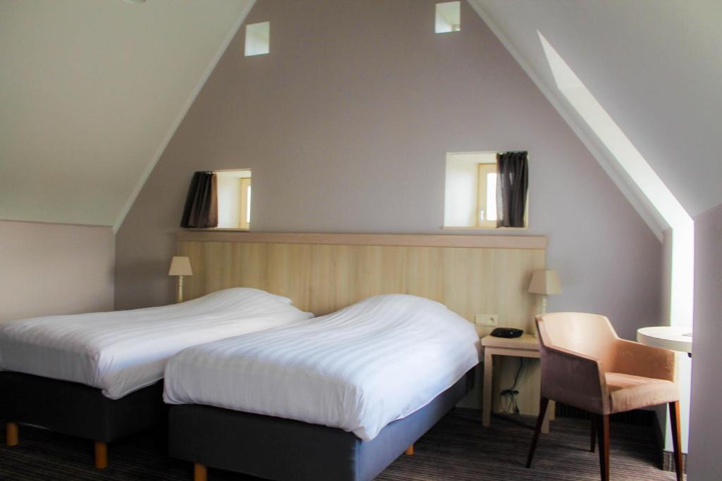 a bedroom with two beds and a table and a chair at La Couronne in Welkenraedt