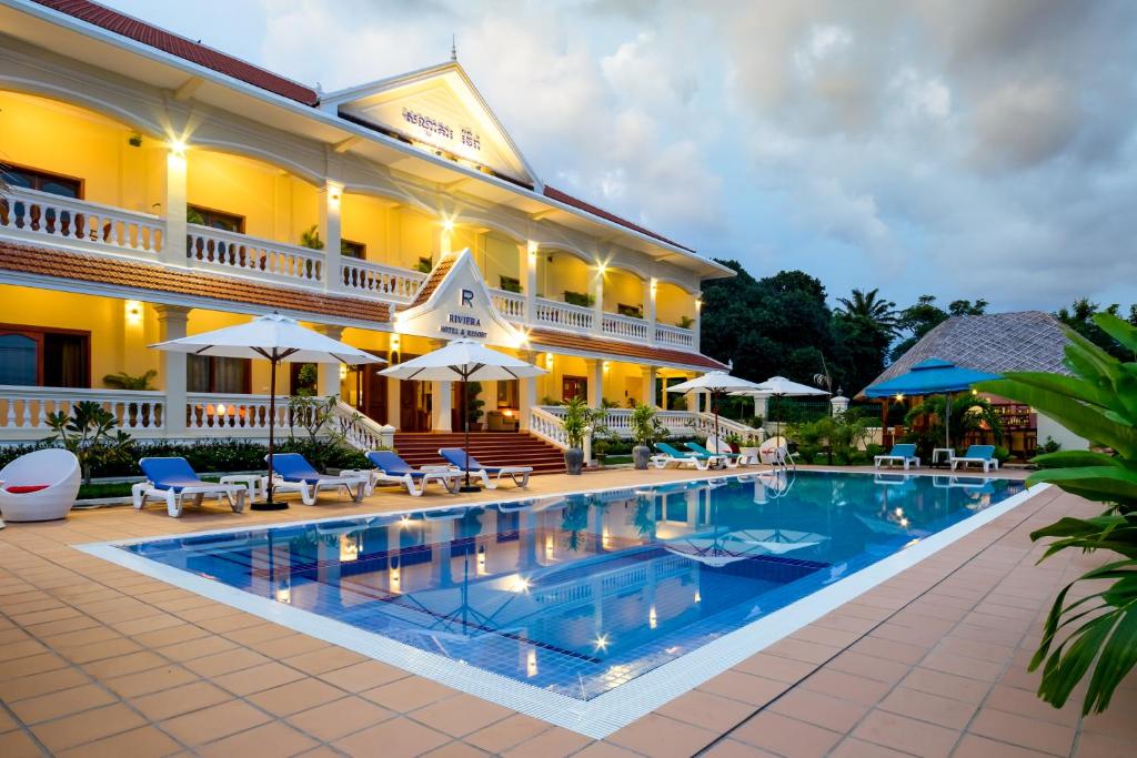 a hotel with a swimming pool in front of a building at Riviera Hotel & Resort Kep in Kep