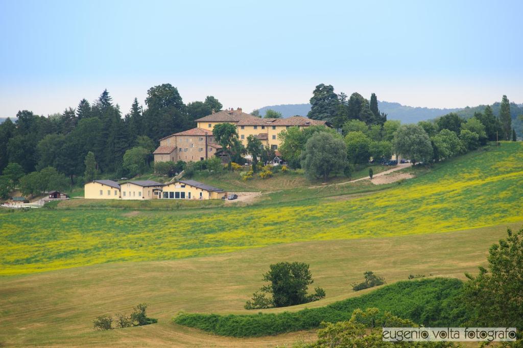 una casa en una colina con un campo de flores en Palazzo Loup Hotel, en Loiano