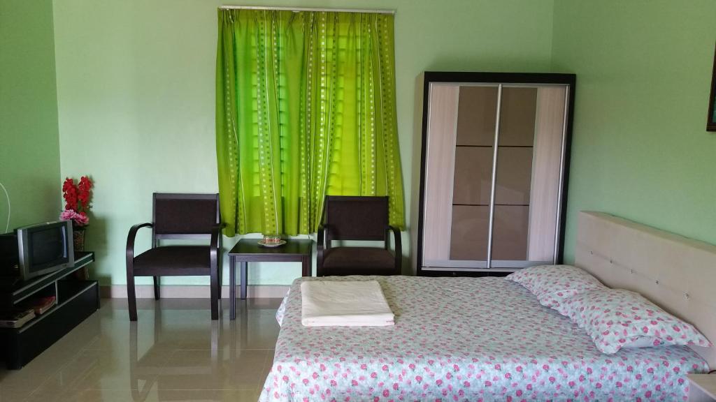 Dhia Irdina Homestay في Paya Rewak: غرفة نوم بسرير وستارة خضراء