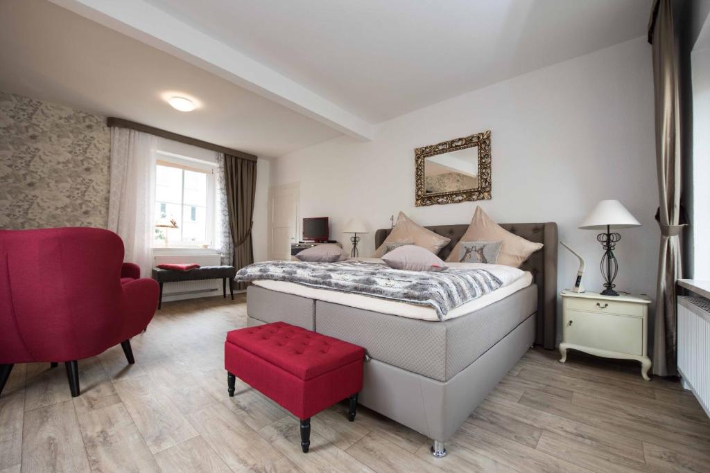 a bedroom with a large bed and a red stool at Sonnenhof Plauen in Plauen