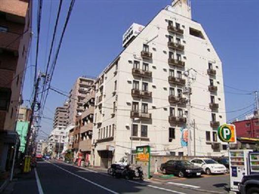 a tall white building on a city street with cars at Soho Asakusa Hotel in Tokyo