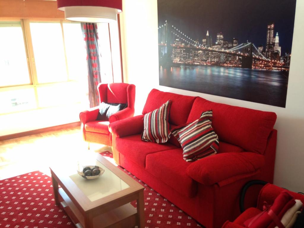 a red couch in a living room with a painting at Apartamento Santander in Santander