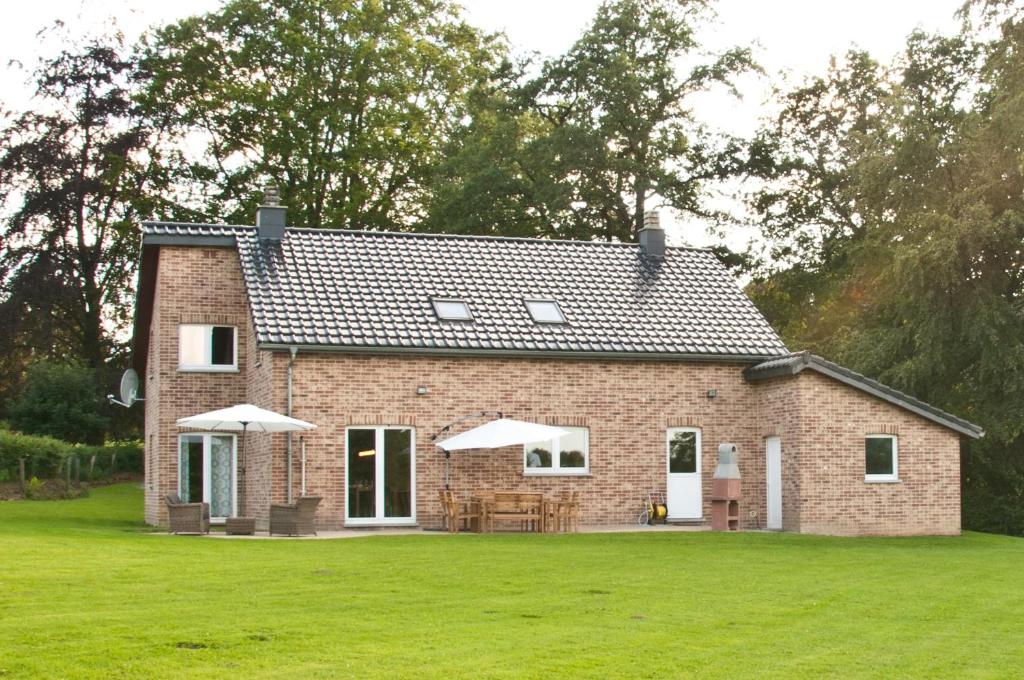 a brick house with a large grassy yard at Gite L'Armandier in Sart-lez-Spa