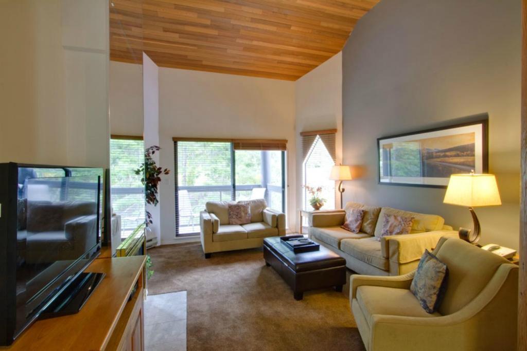 a living room with yellow furniture and a flat screen tv at Ironwood 302 in Whistler