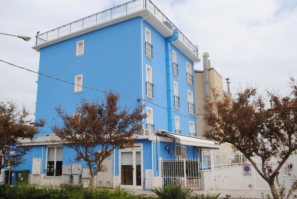 een blauw gebouw met bomen ervoor bij Hotel Eden in Lido di Fermo