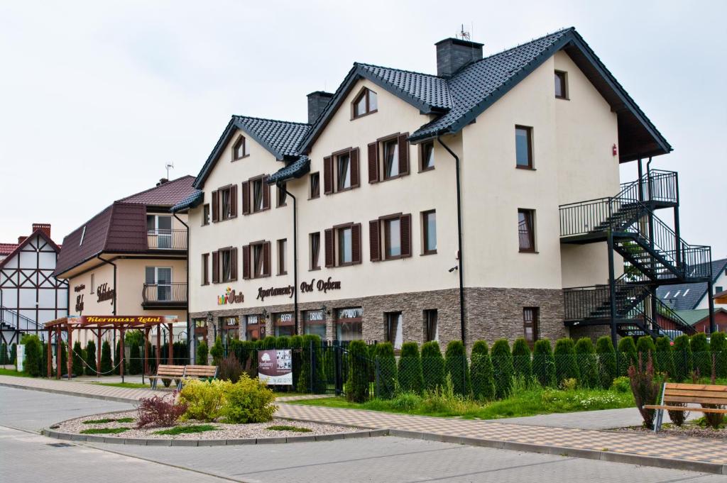 a large white building with a black roof at Apartamenty Pod Dębem in Wicie