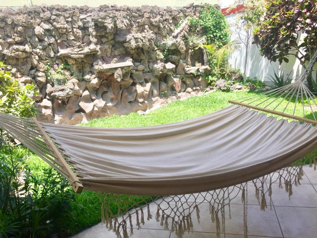 a hammock in a garden with a stone wall at Lima Mini Aparts Monterrico - Cerca Embajada EEUU in Lima