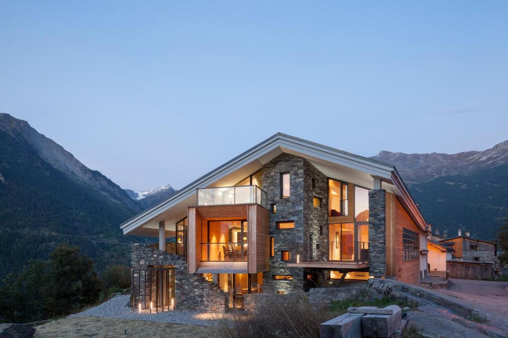 une maison sur une colline avec des montagnes en arrière-plan dans l'établissement Mineral Lodge & Spa, à Villaroger