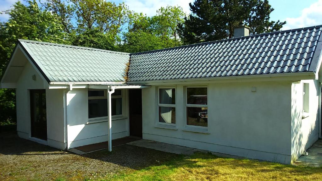 a small white house with a roof at Cosy Lakeside Cottage John's hollow in Headford