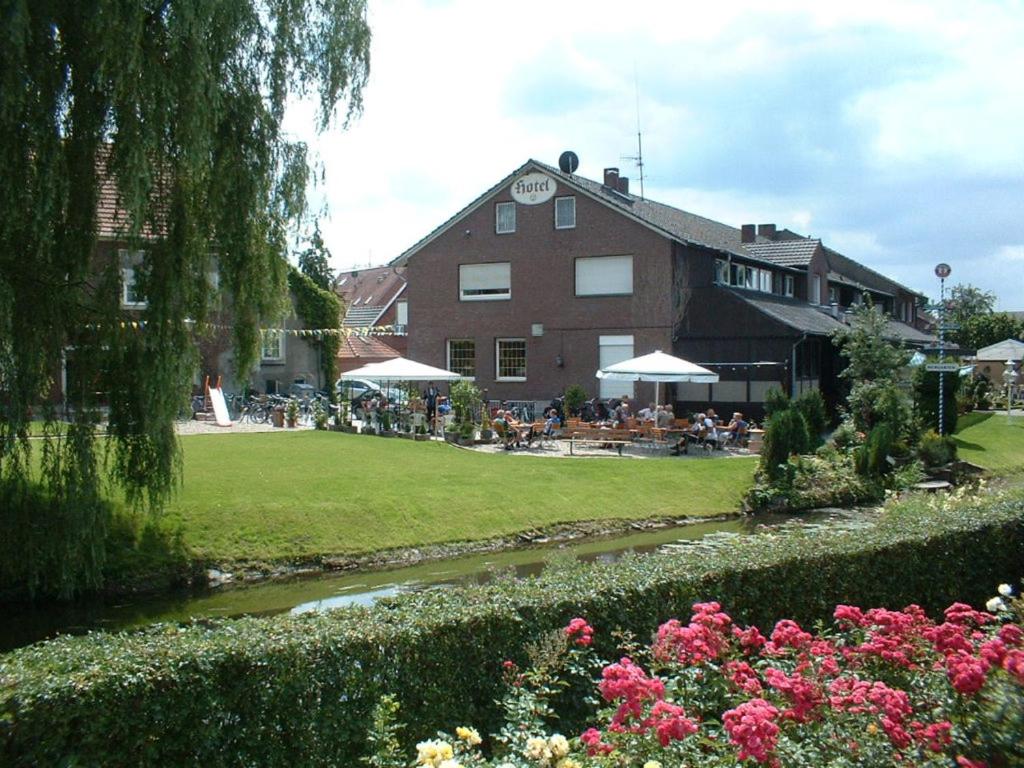 a building with people sitting in a yard with flowers at Hotel Rave in Velen