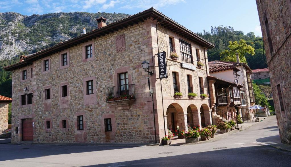 a large stone building with flowers in front of it at Posada de Fidel in Puentenansa