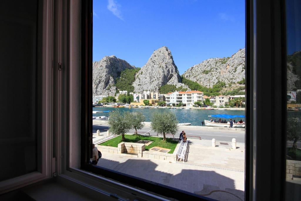 een raam met uitzicht op het water en de bergen bij Apartment Zorica in Omiš