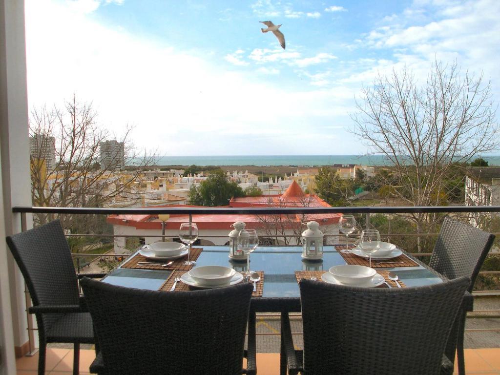 een tafel op een balkon met een vogel boven u. bij Lovely Apartment Alvor in Alvor