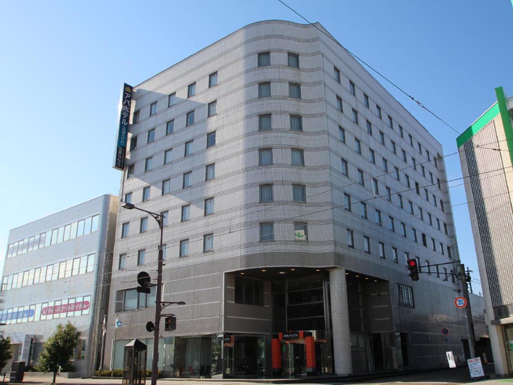 a large gray building on a city street at APA Hotel Takaoka-Marunouchi in Takaoka