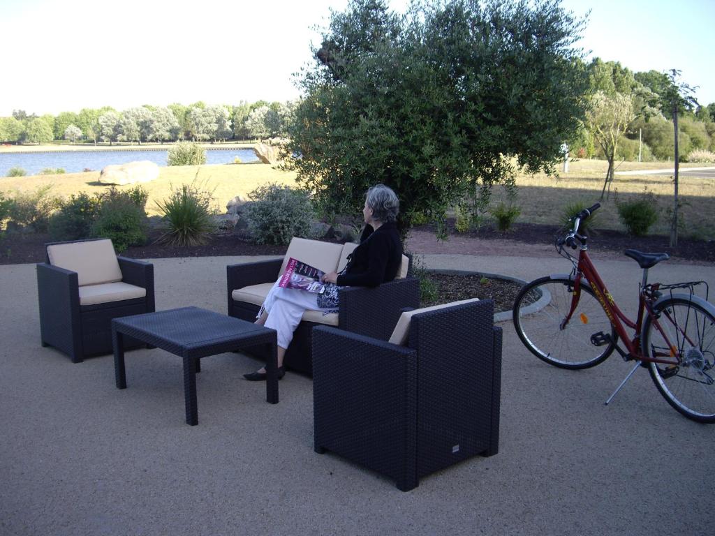 a woman sitting in a chair with a laptop next to a bike at La Terrasse des Oliviers in Mansigné