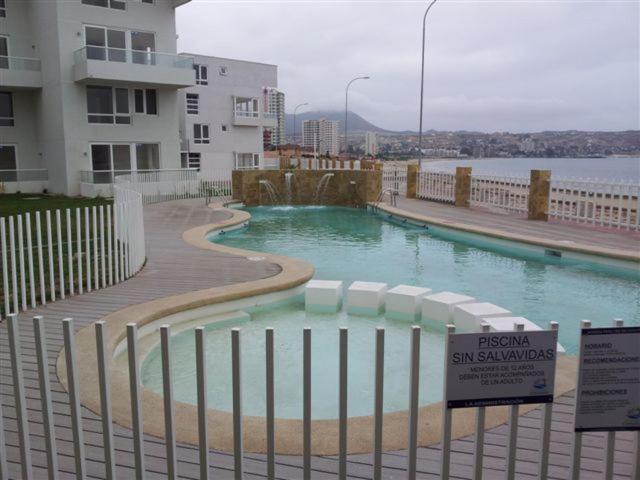 a swimming pool with a sign next to a fence at Condominio Costamar in Coquimbo