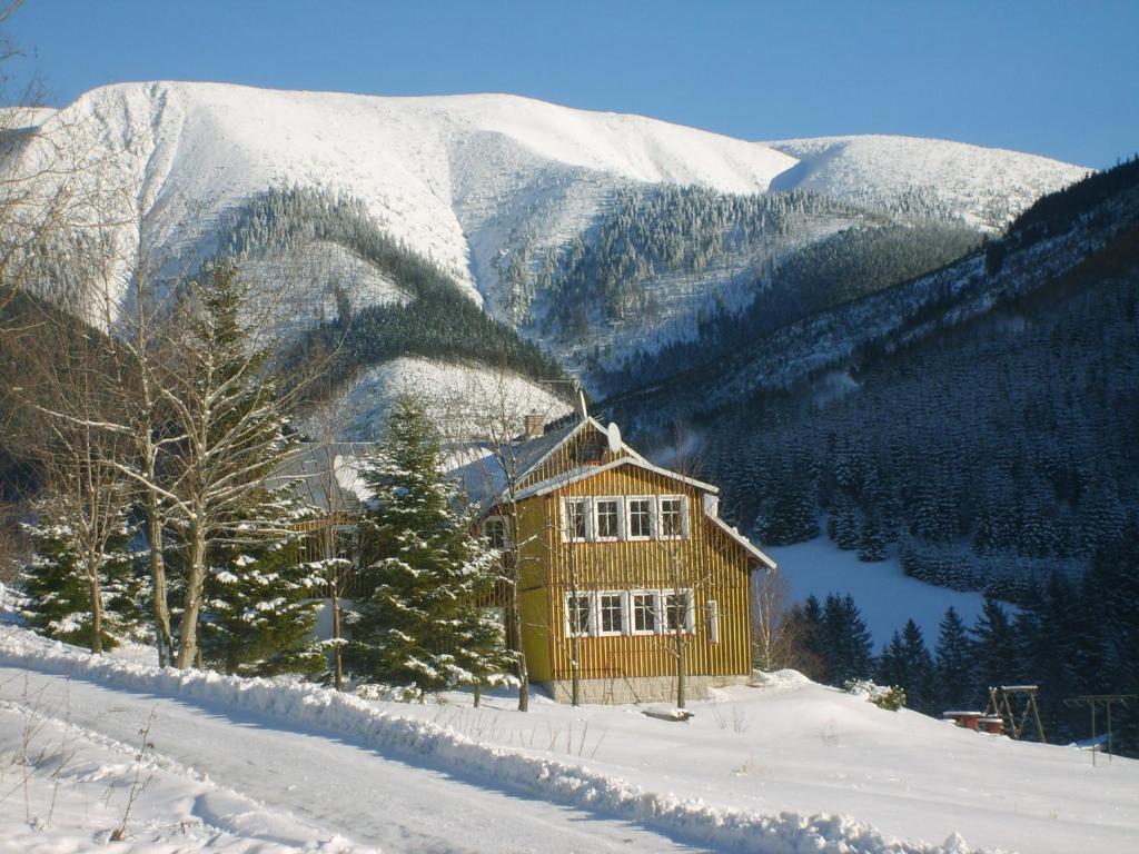 una cabina in legno nella neve con una montagna di Pension 48 a Špindlerův Mlýn