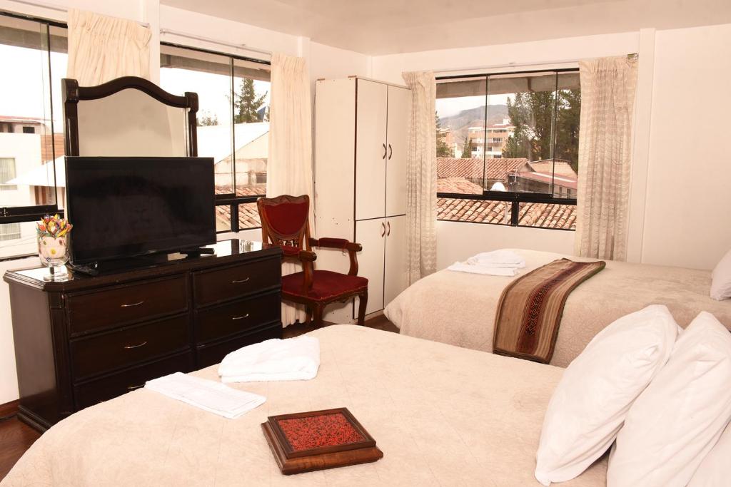 1 dormitorio con 2 camas y un tocador con TV en Cusco Retreat, en Cusco