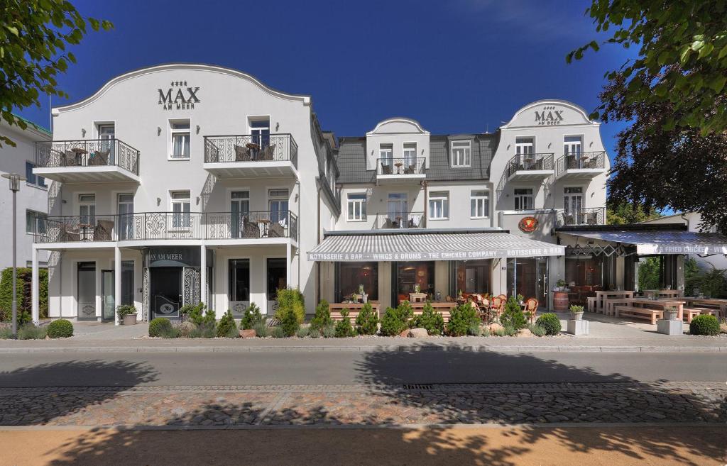 a large white building with tables and chairs in front of it at Hotel Max am Meer Kühlungsborn in Kühlungsborn