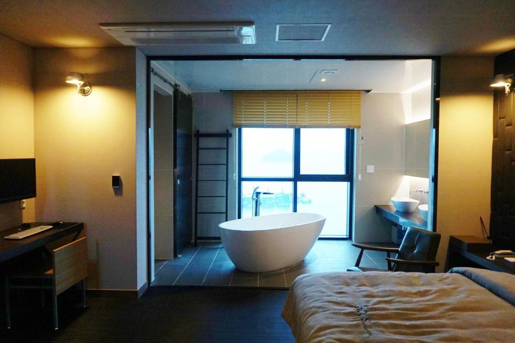 baño con bañera y lavamanos y cama en Louis Boutique Hotel en Changwon