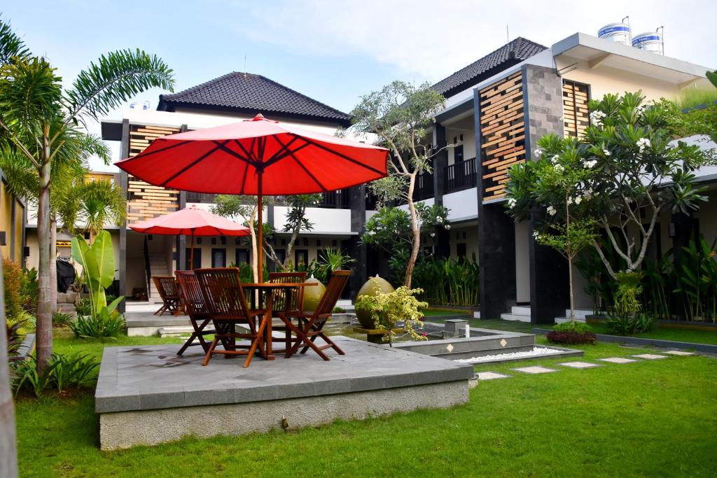a table and chairs with a red umbrella in a yard at Hotel Orizatha in Mataram