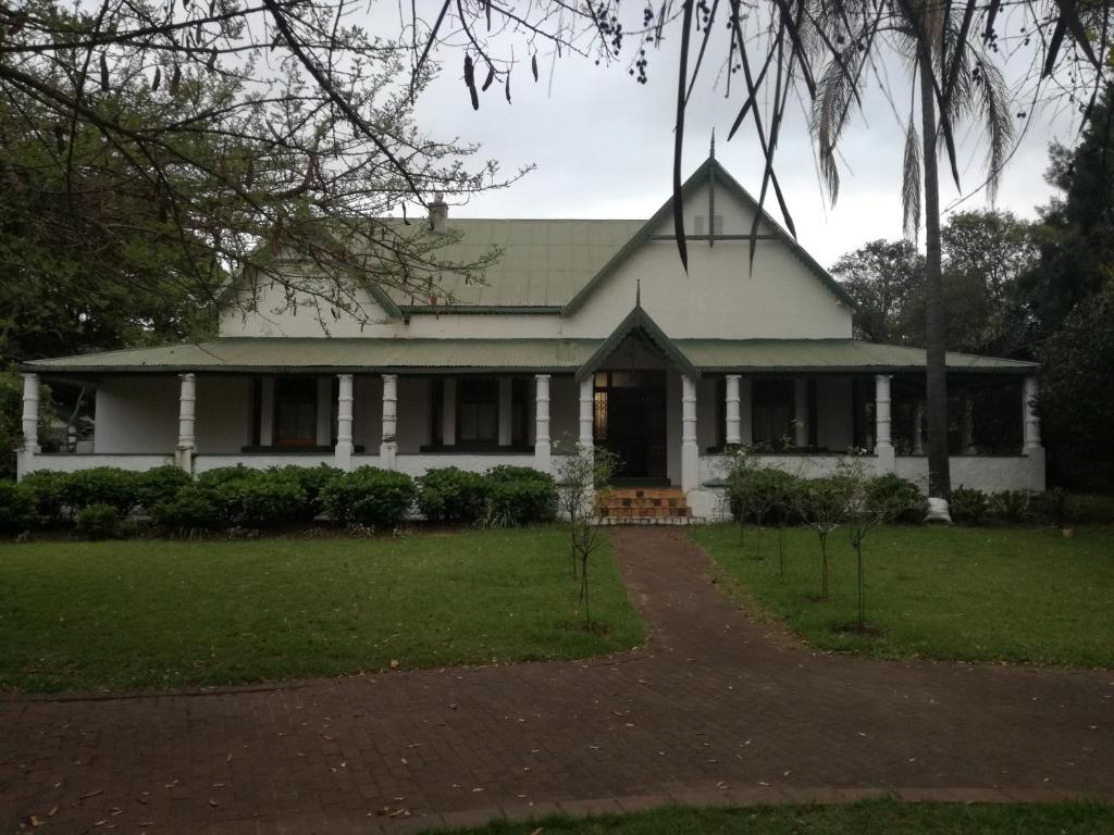 a white house with a porch and a driveway at Cadle House in Vryheid
