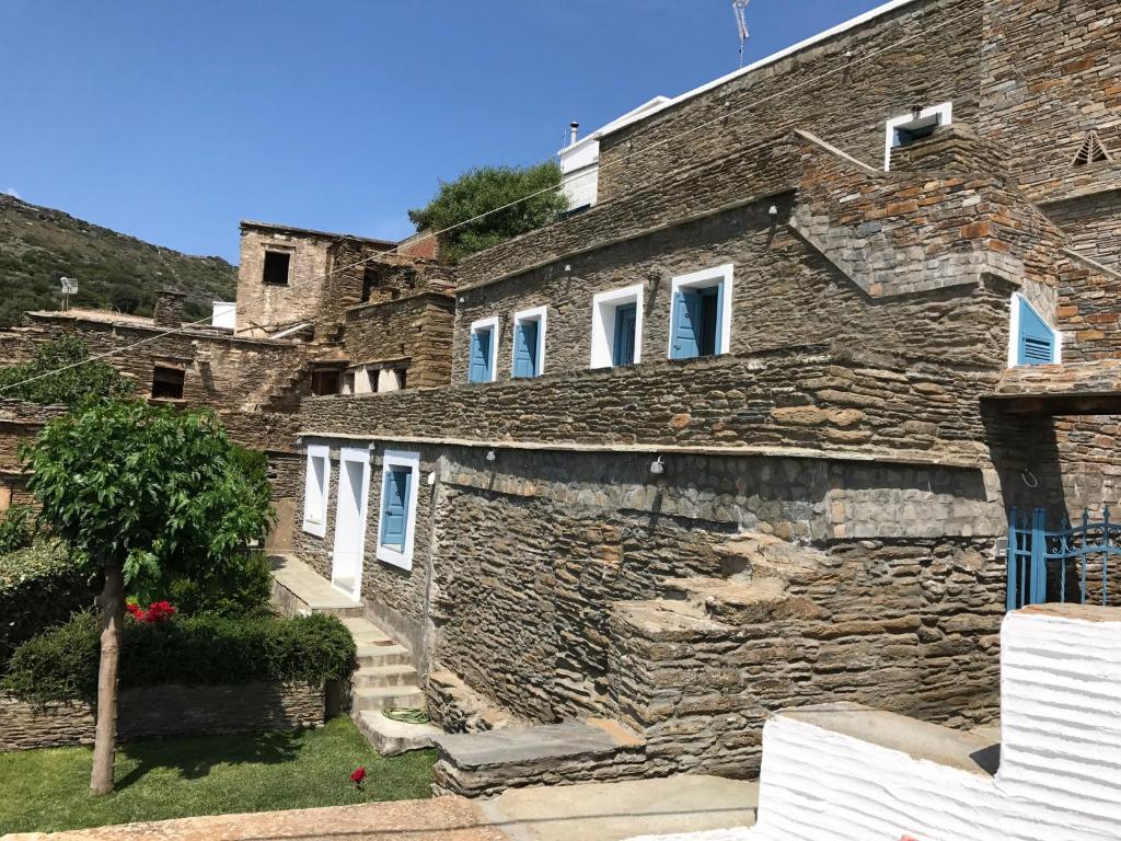 a stone house with white windows and a stone wall at Petra Traditional House in Episkopión