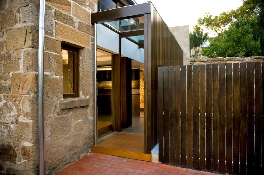 eine offene Tür zu einem Haus mit einem Holzzaun in der Unterkunft Stone Flower in Hobart