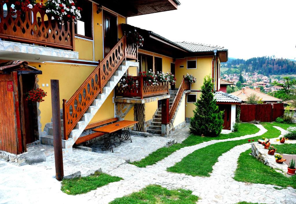 a yellow house with stairs and flowers on it at Guest House Mavrudieva in Koprivshtitsa