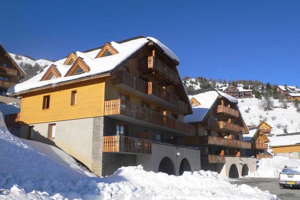 een groot gebouw met sneeuw op de grond bij Chalets de Praroustan by Actisource in Pra-Loup