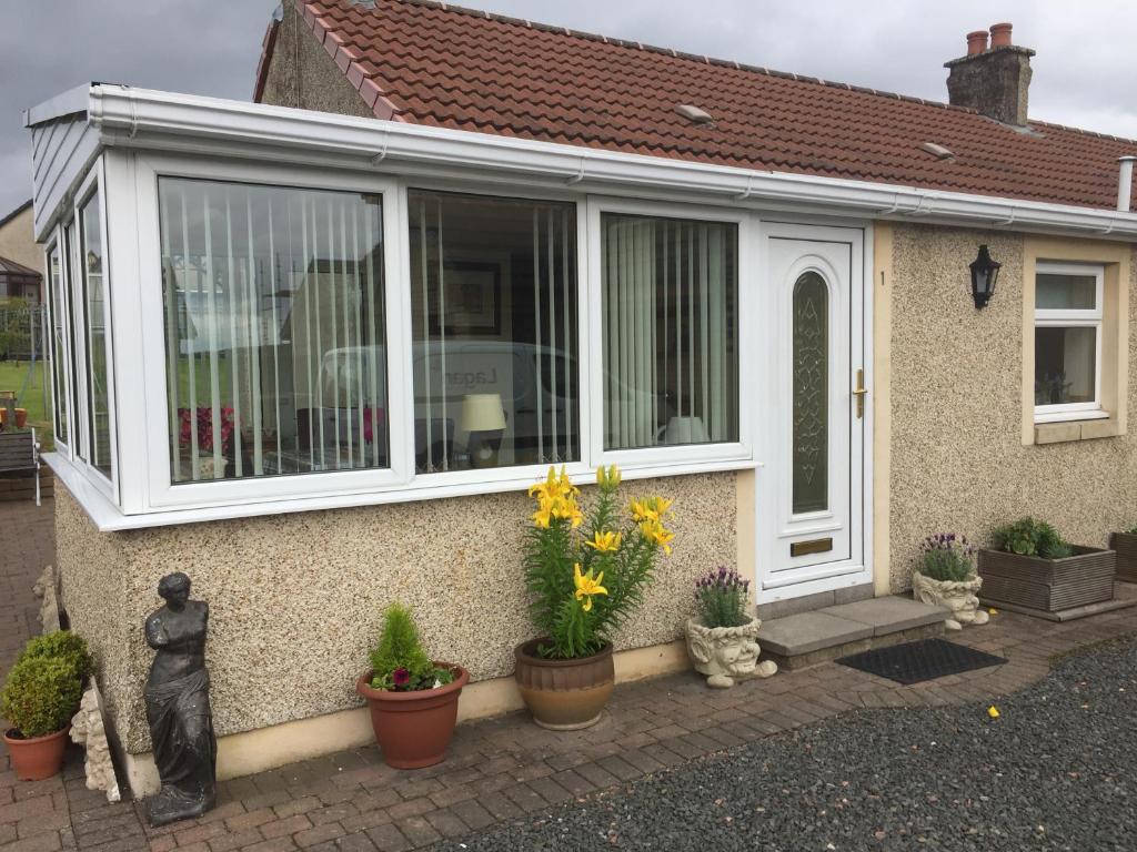 uma casa com janela e vasos de plantas em Honeysuckle-Peaceful Scottish Cottage with Hot Tub em Airdrie