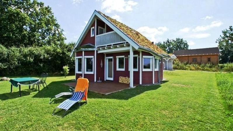 ein rotes und weißes Haus mit einem Tisch und einer Bank in der Unterkunft Norweger Haus am Tollensesee in Groß Nemerow