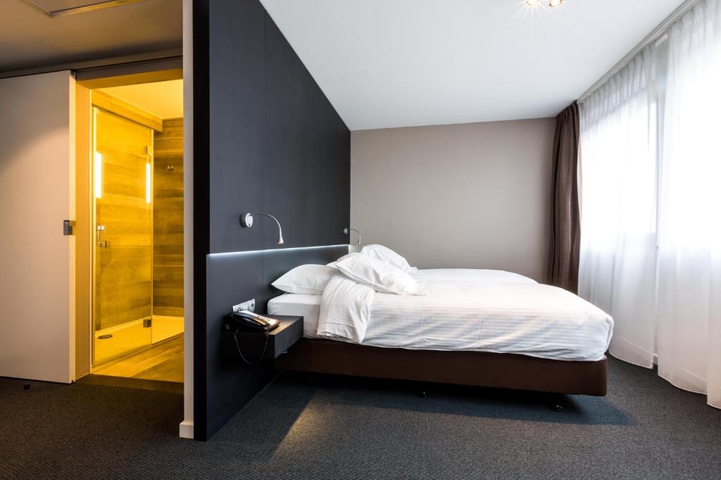 um quarto com uma cama e uma cabina de duche ao nível do chão em Tower Hotel Aalst em Aalst