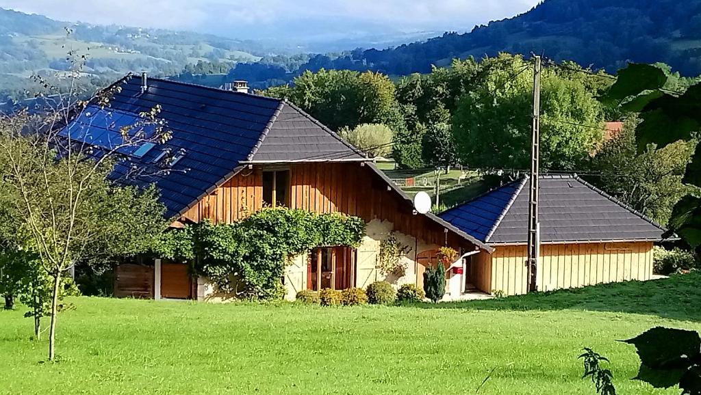 uma casa numa colina com um campo verde em Ferme de la Cochette em Montcel