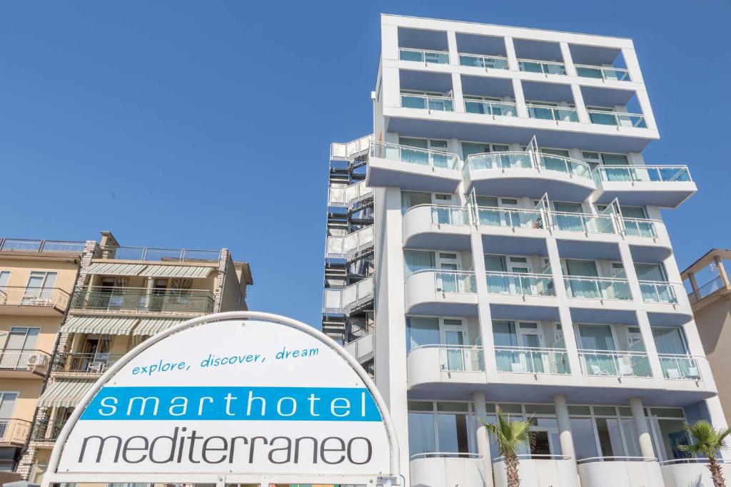 a tall white building with a sign in front of it at Hotel Mediterraneo in Sottomarina