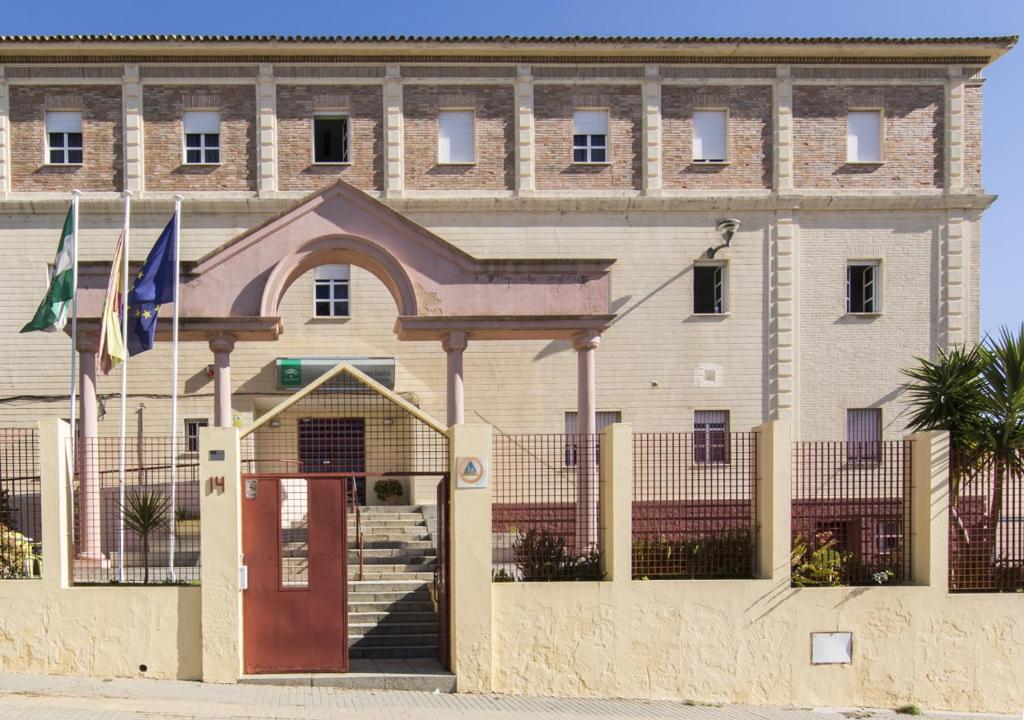 un gran edificio con una puerta roja delante de él en Albergue Inturjoven Huelva, en Huelva