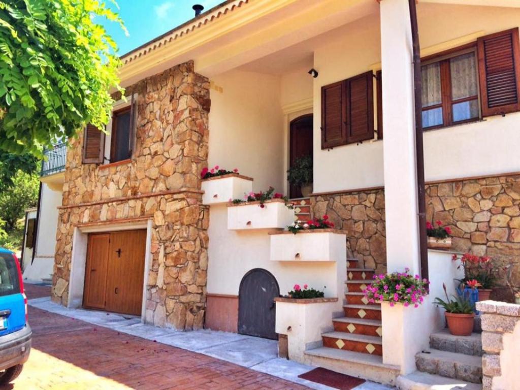 una casa de piedra con escaleras y flores delante en Tanca Noa en Tortolì