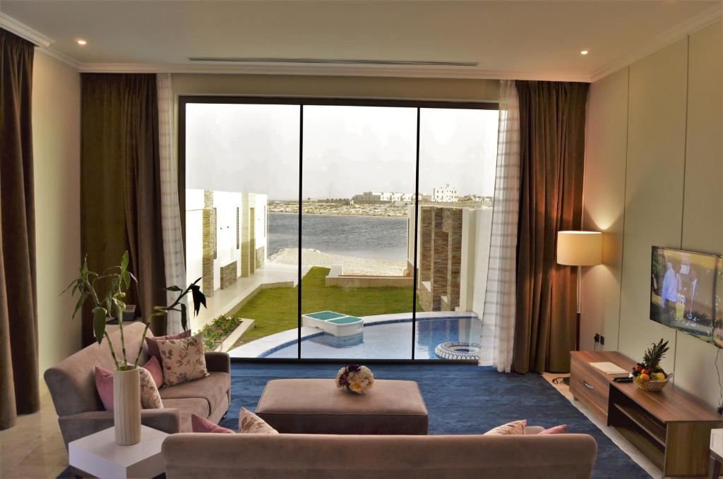 a living room with a large window with a view at Tamara Beach Resort, Al Khobar Half Moon Bay-"Families Only" in Half Moon Bay
