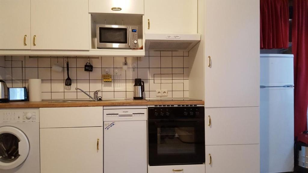 cocina con armarios blancos y microondas en Ferienwohnung Roch GbR, en Berlín