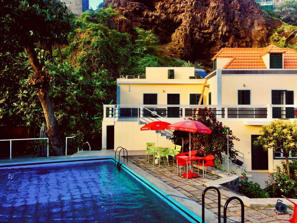 a pool with chairs and umbrellas next to a house at Casa Santa Barbara Deluxe in Ribeira Grande