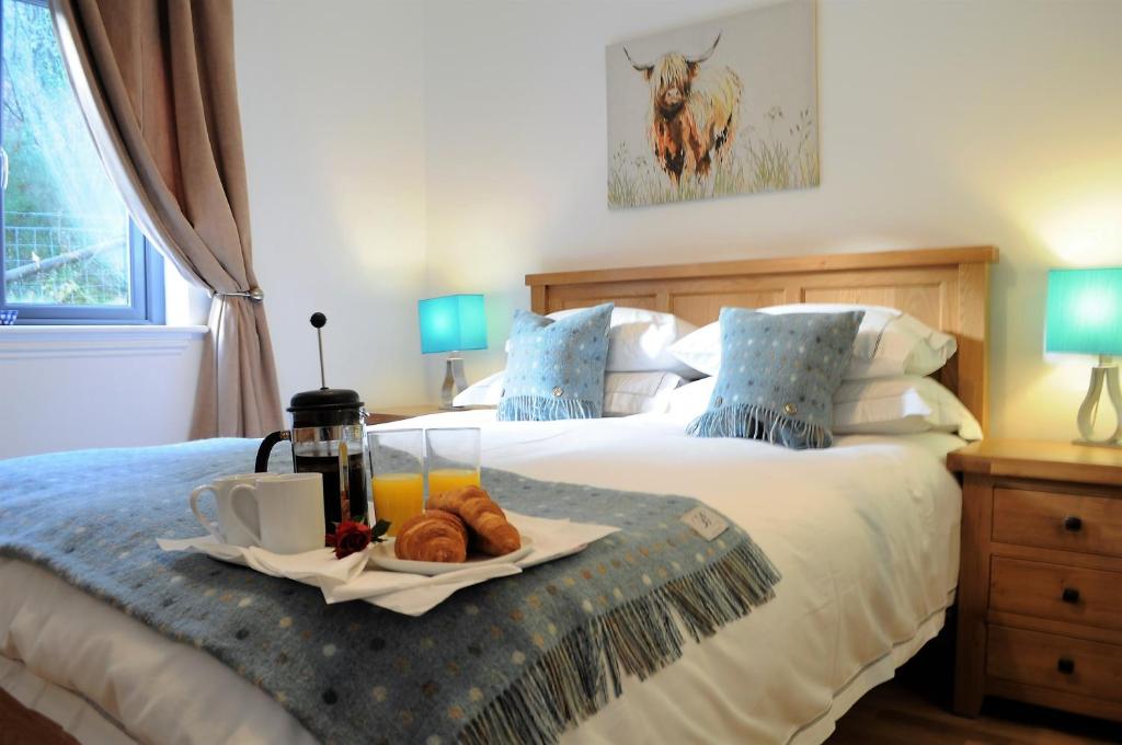 - une chambre avec 2 lits et un plateau de nourriture sur le lit dans l'établissement Bluebell Cottage with Hot Tub, à Ballachulish