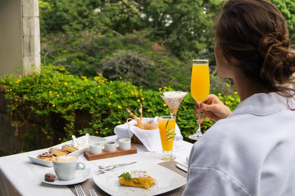 a woman sitting at a table with food and drinks at AcquaSanta Lofts Hotel in Cali