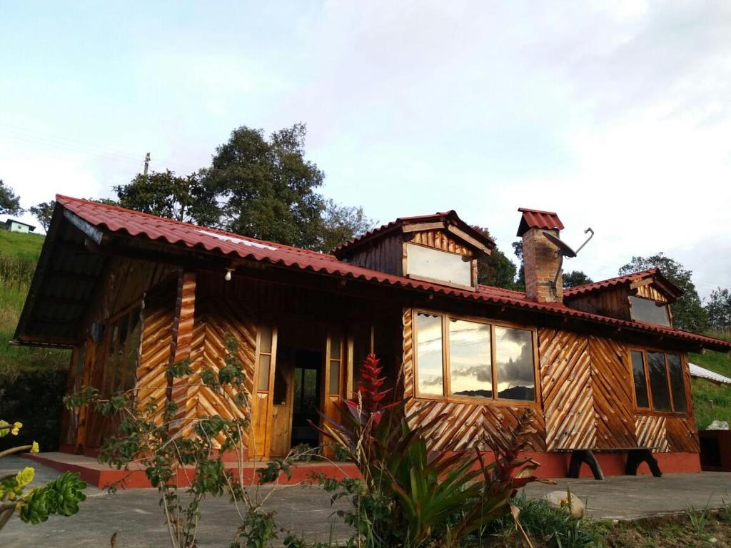 uma cabana de madeira com uma chaminé por cima. em CASA LA KOCHA, Cabin, Hostal en la Laguna de la Cocha em El Encano